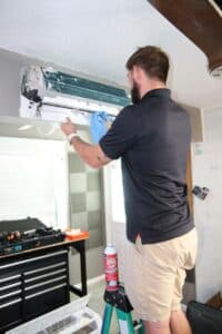 Service Emperor technician cleaning the air filter on a minisplit HVAC unit